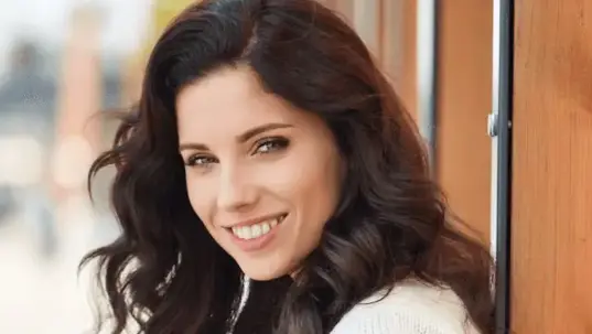 A smiling woman with dark hair and light eyes