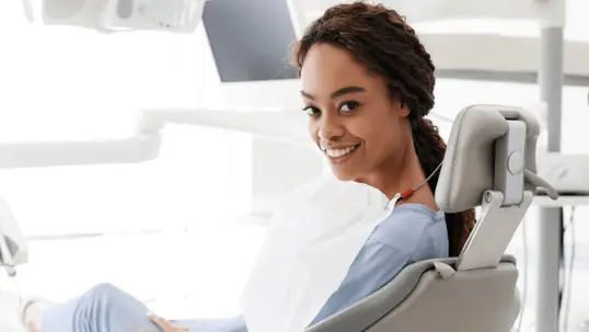A woman seated in a bright, modern dental chair