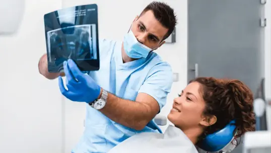 dentist in a mask explaining a patient's x-ray