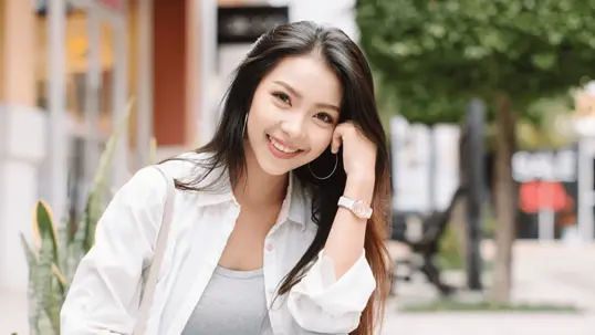 A smiling woman wears a white shirt over a gray top