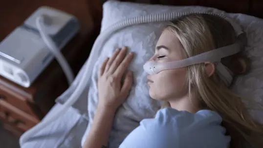 A person sleeps wearing a CPAP mas